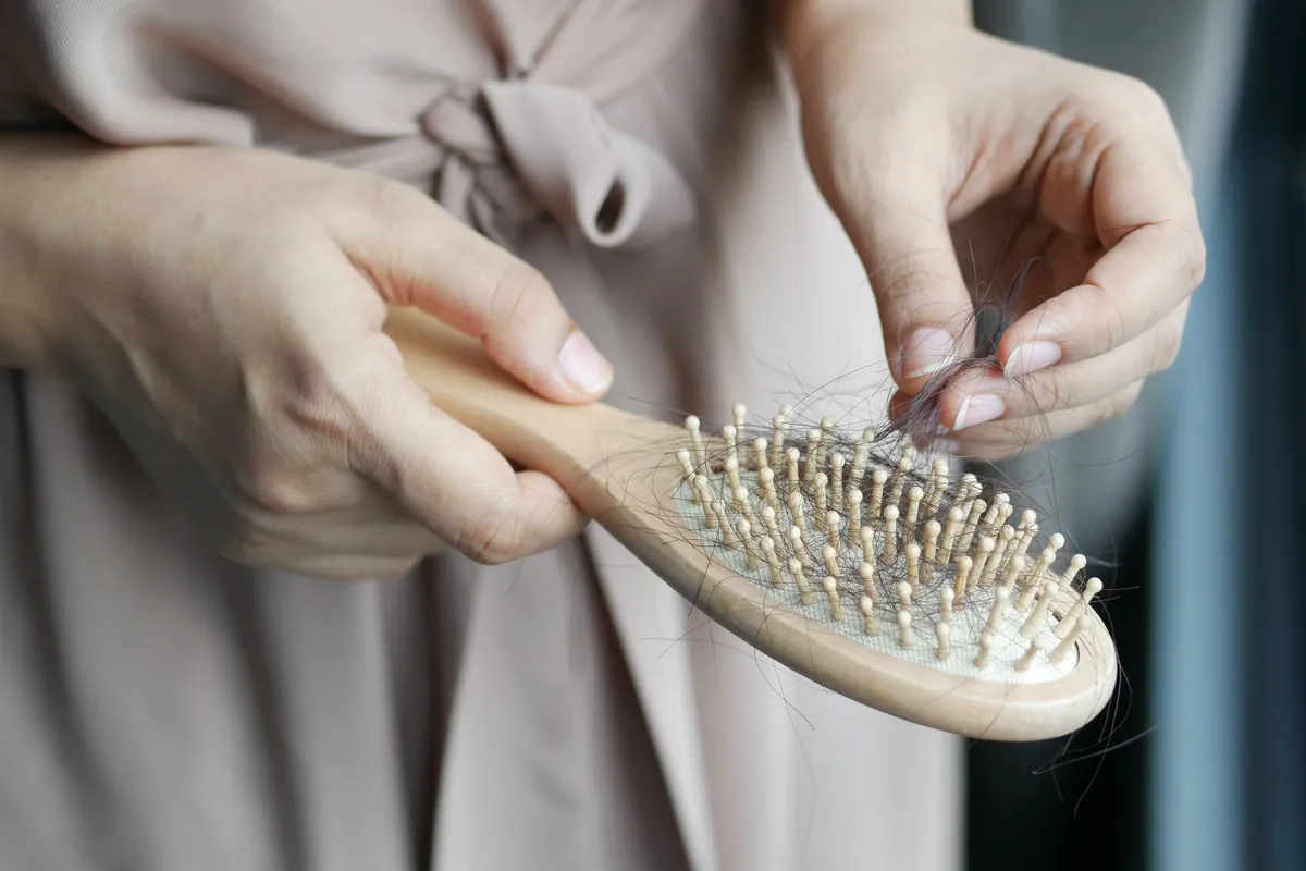 Manos quitando pelo caído de un cepillo de madera